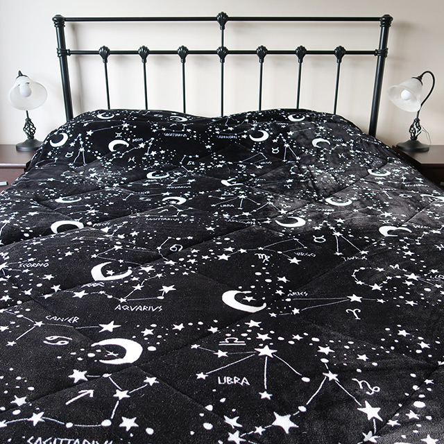 A bed covered with Killstar's Starmap Comforter
