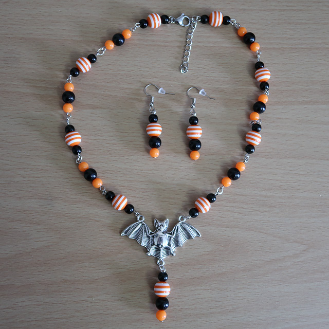 A black, white and orange beaded necklace with a bat centrepiece