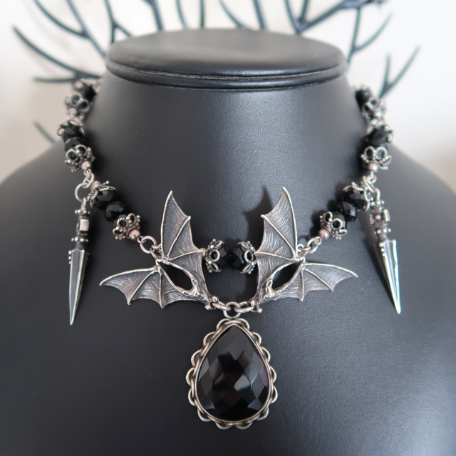 A black glass beaded necklace featuring two bats holding an onyx drop pendant