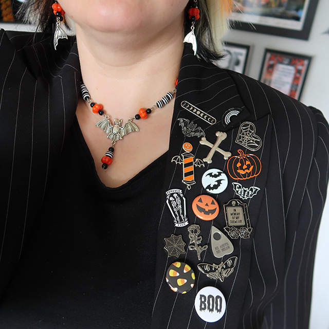 Close up of bat necklace and Halloween-themed pins